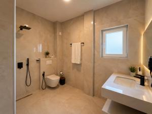 a bathroom with a toilet and a sink and a window at Domi Drymades in Dhërmi +66 photos