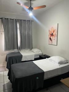 two beds in a room with a ceiling fan at Carmo Palace Hotel in Carmo do Paranaíba