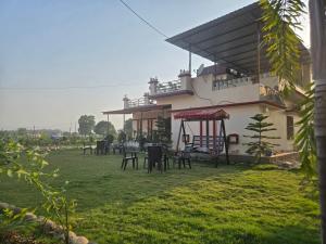 a house with chairs and tables in a yard at Jim Corbett Guest House in Jhirna
