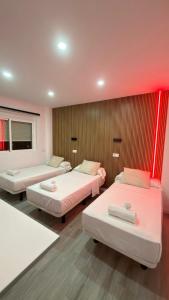 three beds in a room with red lighting at El Chalecito De Alicante in El Campello +10 photos