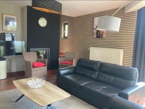 a living room with a black leather couch and a table at Gites en ardennes & wellness - Ovifat - Coquelicots & Orchidees in Ovifat