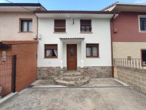 a white house with a door and a brick wall at Villa Playa del Silencio in Castañeras +7 photos