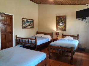 a room with two beds and a tv on the wall at Hotel Villa Paraiso in Santo Domingo