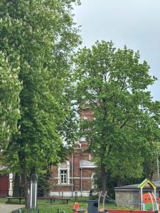 an old brick building with trees in front of it at Studio between two stations in Šiauliai