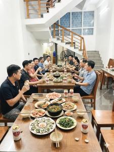 a group of people sitting at a table eating food at Mùi Oanh Homestay sát biển in Sầm Sơn