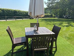 a wooden table with an umbrella and two chairs at Old Dairy Farm Glamping in Emsworth +8 photos