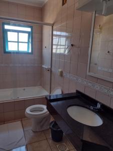 a bathroom with a sink and a toilet and a tub at hotel castelo in Cidreira +22 photos
