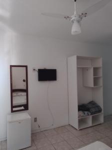 a white room with a television and a mirror at hotel castelo in Cidreira
