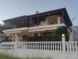 a house with a white fence in front of it at Two-floor house next to sea in Loutraki