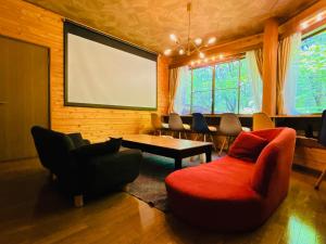 a room with a large screen and a couch and chairs at コテージちゃ豆ん家 in Nasu