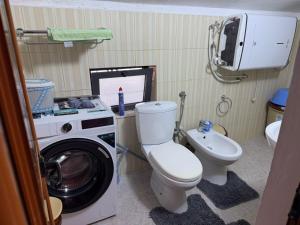 a bathroom with a washing machine and a toilet at Le Toit du Ciel in Pukë