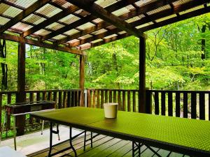 a green table on a deck with a pergola at コテージちゃ豆ん家 in Nasu