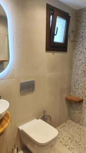 a bathroom with a toilet and a sink and a window at Saint Andrews Bay in Milina