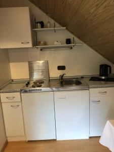 a kitchen with white cabinets and a sink at Gemütliches Studio am Riepen in Hameln +6 photos
