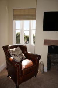 una silla de cuero marrón en la sala de estar con chimenea en No. 23 at The Moorings, Chester en Chester