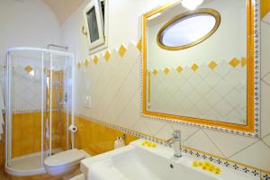 un bagno con lavandino, WC e specchio di Casa La Ulivella a Praiano Altre 12 foto