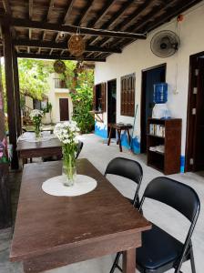 a wooden table with chairs and a vase of flowers on it at Wave Cafe INN in General Luna