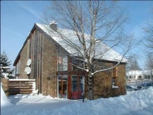 a brick building with a tree in the snow at Gites en ardennes & wellness - Ovifat - Coquelicots & Orchidees in Ovifat