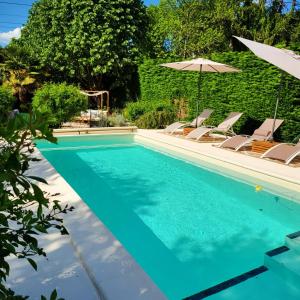 a swimming pool with chairs and an umbrella at La Cale de la Clauderie in Rigny-Ussé