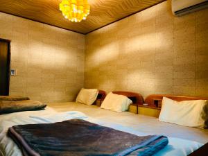 a bedroom with two beds and a chandelier at コテージちゃ豆ん家 in Nasu
