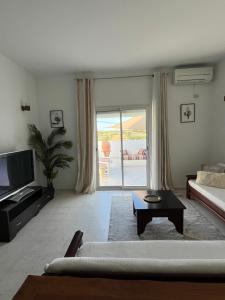 a living room with a couch and a tv and a window at résidence les oliviers in Soliman