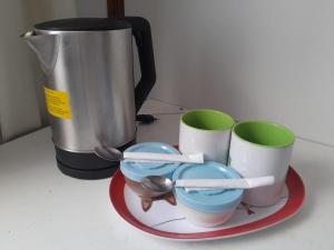 a coffee pot and three cups and spoons on a plate at Alojamiento Punta Arenas in Punta Arenas