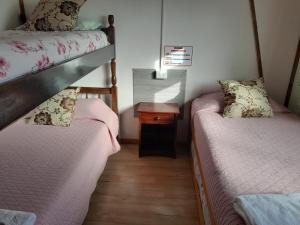 a room with two beds and a night stand with a table at Alojamiento Punta Arenas in Punta Arenas