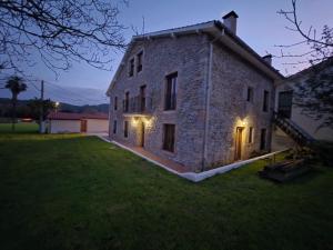 an external view of a stone house at night at Alojamientos ADRIMAR in Arnuero