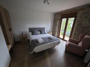 a bedroom with a bed and a window and a chair at Alojamientos ADRIMAR in Arnuero