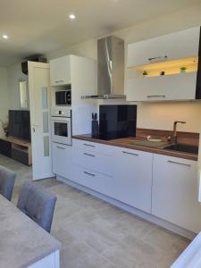 a large kitchen with white cabinets and a sink at Appart Allée des chênes in Furiani