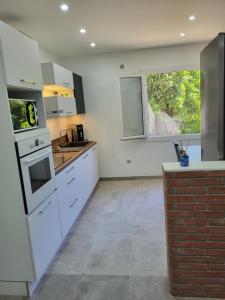 a kitchen with white appliances and a brick wall at Appart Allée des chênes in Furiani +3 photos