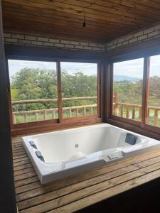 a large white bath tub in a room with windows at Luz de Arcturus, Chalé com jacuzzi aquecida in Imbituba +69 photos