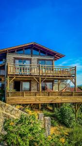 a large house with a wooden deck in front of it at Luz de Arcturus, Chalé com jacuzzi aquecida in Imbituba