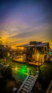 a building with a sunset in the background at Luz de Arcturus, Chalé com jacuzzi aquecida in Imbituba