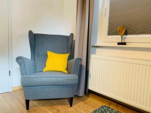 a blue chair with a yellow pillow in a room at Zwei Apartments - ein Haus - Alles fußläufig - Altstadt, Wanderwege, Freibad und Restaurants in unmittelbarer Nähe in Schmallenberg