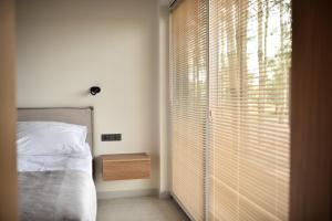 a bedroom with a bed and a window with blinds at Szept Lasu in Żabiczyn