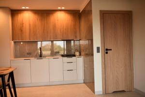 a kitchen with white cabinets and a wooden door at Szept Lasu in Żabiczyn