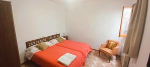 a bedroom with a red bed and a chair at La Quinta Terra Alta Matarraña in Caseras +25 photos