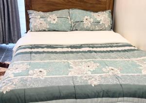 a bed with a green and white comforter and pillows at Perfect Homes Namugongo in Kasiyirize