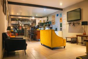 a living room with a yellow chair and a bar at Soul Hostel Av Paulista Bela Vista 1 in São Paulo