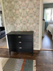 a black dresser in a room with a wall at Känslans in Årjäng