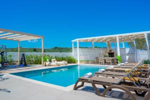 a swimming pool with chaise lounges and lounge chairs at Spartakos Villa Resort - Slow Living Retreat collections With Private Pools in Planos +110 photos