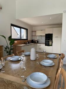 a dining room table with plates and wine glasses at Le Cottage Bigouden in Combrit