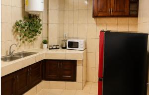 a kitchen with a black refrigerator and a microwave at Appartement cozy Bonamoussadi, WIFI & Goupe électrogène in Douala +2 photos