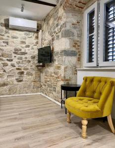 a yellow couch in a room with a stone wall at APARTMAN B in Split