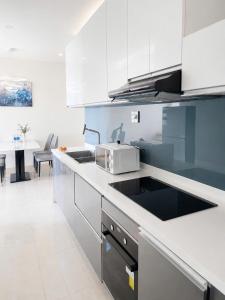 a kitchen with white cabinets and a sink and a table at Monarchy Luxury Serviced Apartments - By Charm Homestay Vietnam in Danang