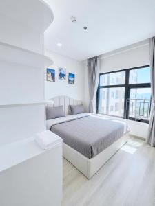 a white bedroom with a bed and a large window at Monarchy Luxury Serviced Apartments - By Charm Homestay Vietnam in Danang +43 photos