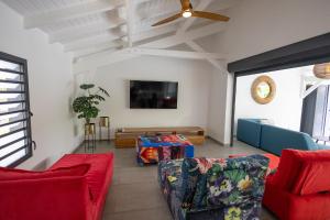 a living room with red and blue couches and a tv at Majesty Palm Hôtel in Saint-François