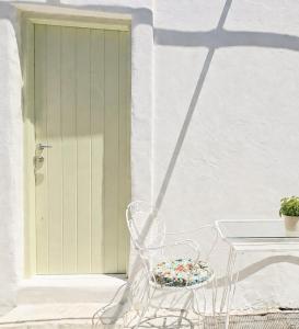 a white chair sitting in front of a door at Maison Jolie in Vlachopoulátika