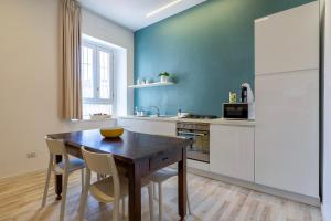 a kitchen with a wooden table and chairs and a kitchen with blue walls at RelaisApartments PORTO in Alghero
